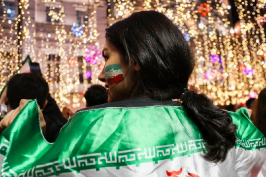 Iraanse supporter met vlag om haar schouders 