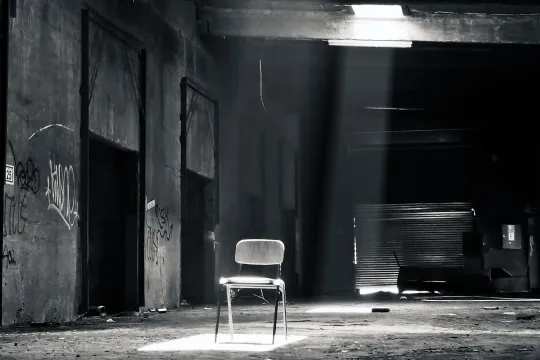een donkere steeg zwart wit met een verlichte stoel