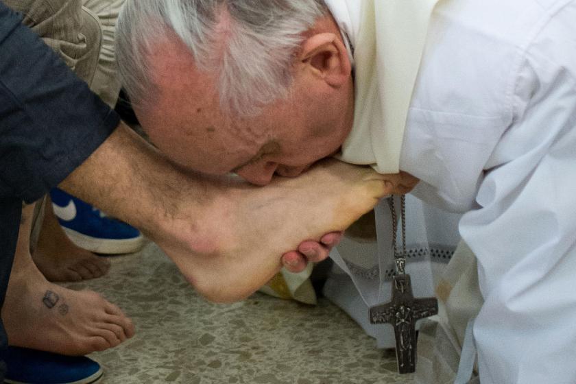 This handout picture released by the Vatican press office on March 28, 2013 shows Pope Francis (R) kissing the feet of a young offender after washing them during a mass at the church of the Casal del Marmo youth prison on the outskirts of Rome as part of Holy Thursday. Pope Francis washed the feet of 12 young offenders including two girls at a Rome prison on Thursday in an unprecedented version of an ancient Easter ritual seen as part of an effort by the new pope to bring the Catholic Church closer to the n