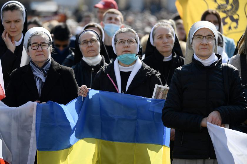 Nuns hold the Ukranian flag as Pope Francis delivers the Sunday Angelus prayer from the window of his study overlooking St Peter's Square at the Vatican on March 6, 2022. 