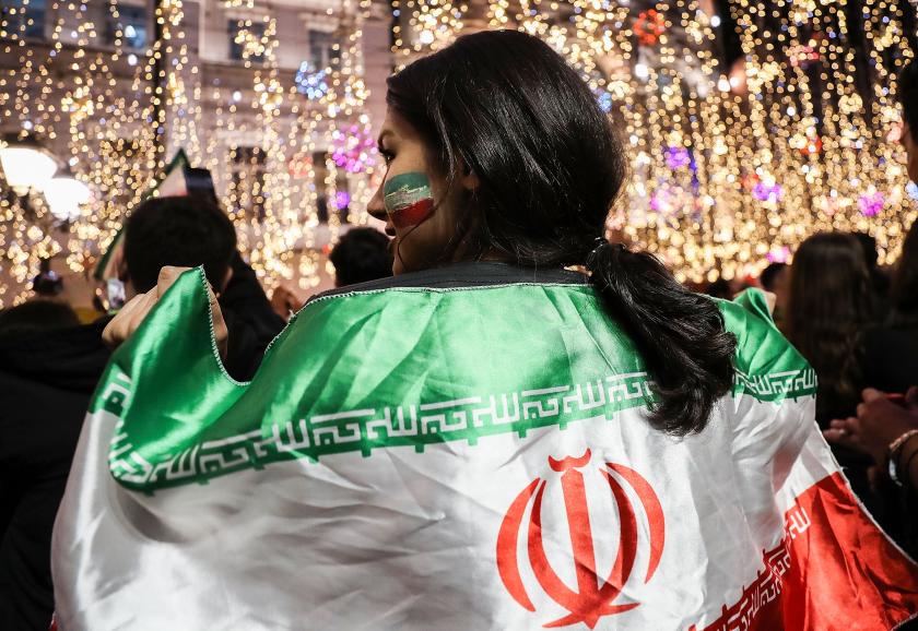 Vrouw met de Iraanse vlag over haar schouders gedrapeerd