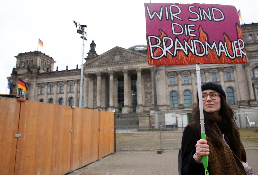 A demonstrator holds a placard which reads 'We are the firewall' in front of the Reichstag building in Berlin, Germany on February 3, 2024, during a rally called for by international non-profit organisation 'Hand in Hand' to protest against right-wing politics. Thousands of protesters gathered outside the Reichstag building in central Berlin to demonstrate against racism and the far right, with many more peaceful rallies planned across the country. Adam BERRY / AFP