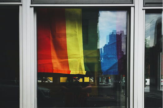 Een regenboogvlag hangt in een raam 