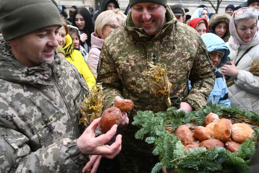Ukrainian servicemen hold "didukh", bunches of wheat to symbolise sacrifice and taste traditional doughnuts during Christmas Eve celebration in Lviv, on December 24, 2023, amid the Russian invasion of Ukraine. Ukrainians attend Christmas Eve services as they prepare to celebrate Christmas Day on December 25 for the first time, after the government changed the date from the Orthodox Church observance of January 7 in a snub to Russia, on December 24, 2023. YURIY DYACHYSHYN / AFP