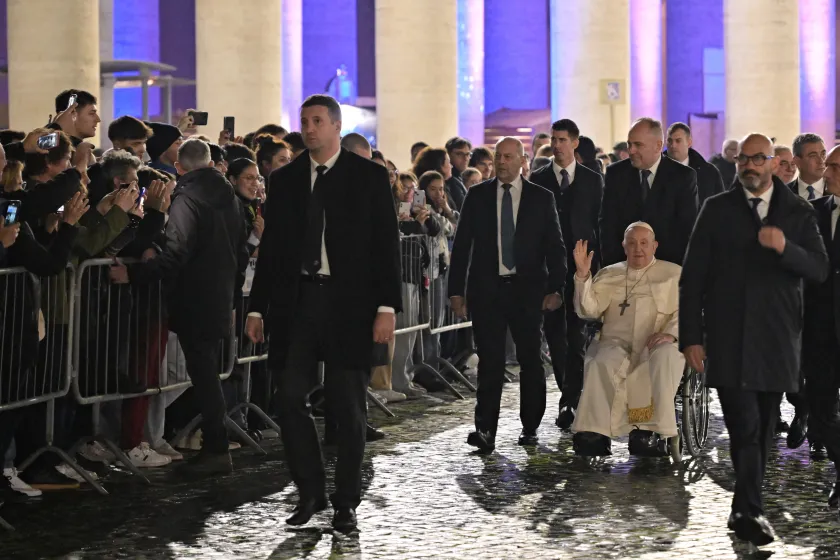 Pope Francis (C), flanked by officials, waves to onlookers while moving in a wheelchair across St. Peter's Square in The Vatican on December 31, 2023. Andreas SOLARO / AFP