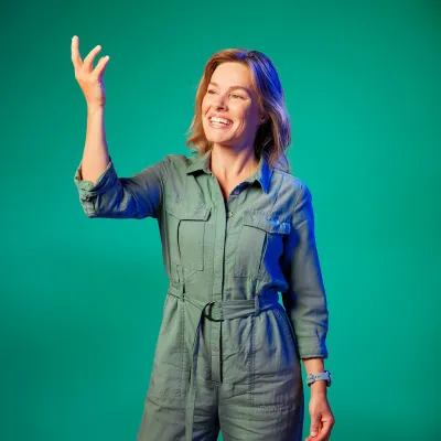 Marieke Schatteleijn poseert voor een groene achtergrond met een hand omhoog