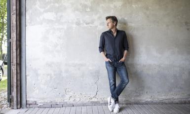 Tom Kleijn staand tegen een grijze muur